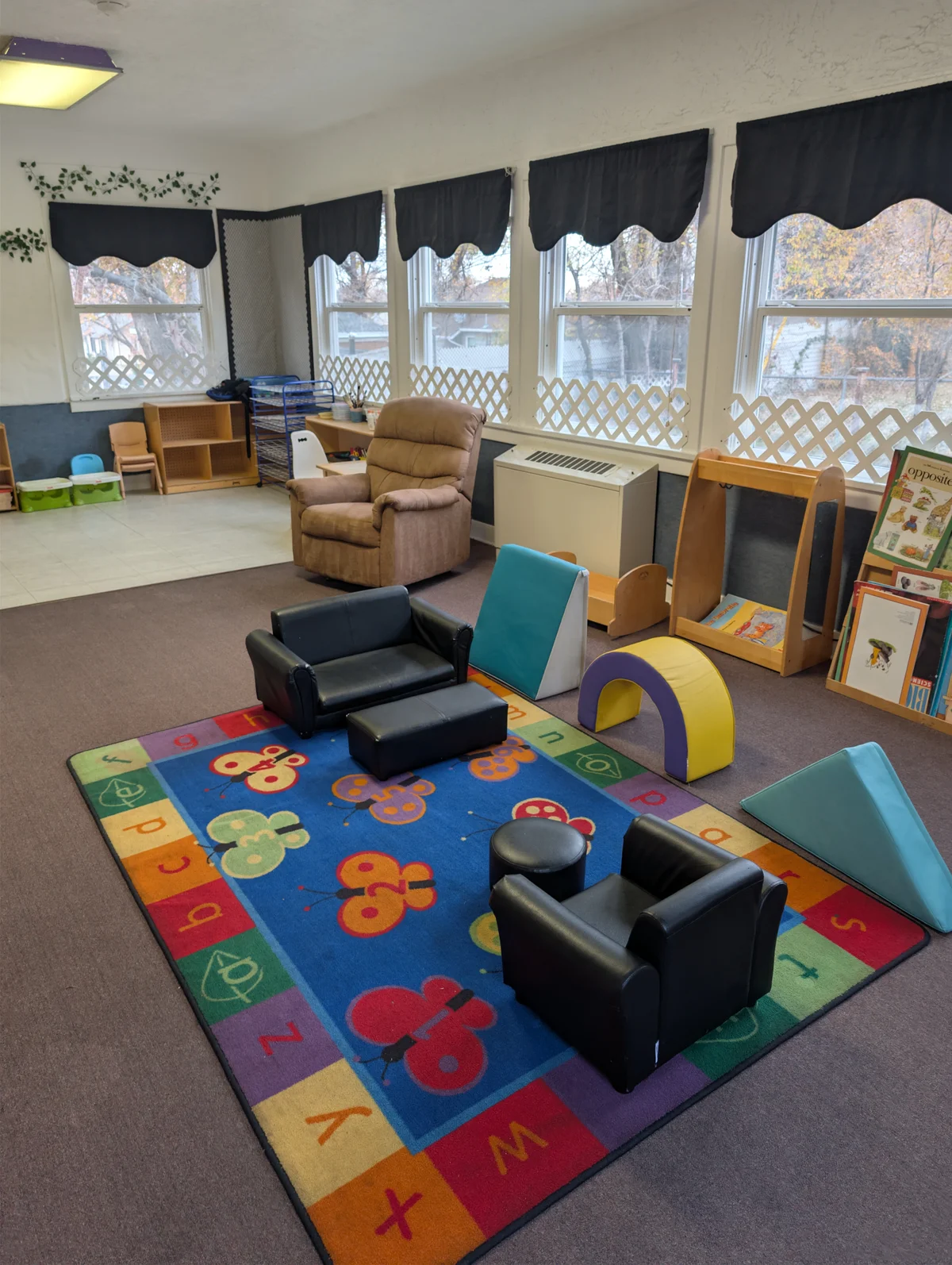 Spacious toddler activity room with soft learning rug, climbing blocks and mini chairs